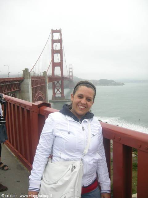 Smiling woman in white jacket in front of the foggy Golden Gate Bridge