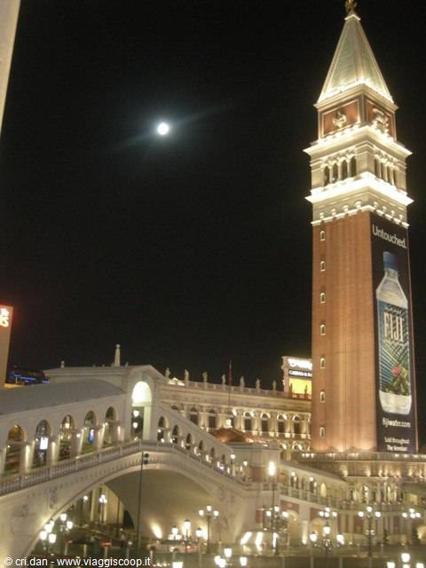 Replica of St Mark's Campanile and Rialto Bridge lit up at night, moon above