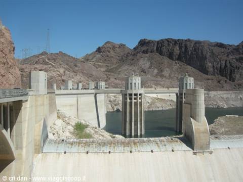 Hoover Dam concrete walls and intake towers amid desert rocks, blue Colorado below