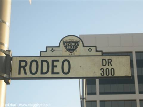 Rodeo Drive street sign in Beverly Hills against building and blue sky