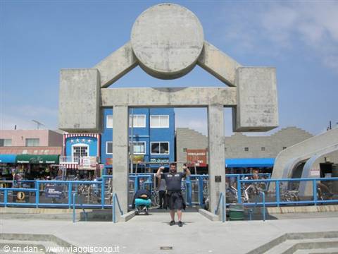 Tourist flexes his biceps under the concrete Venice Beach entrance arch