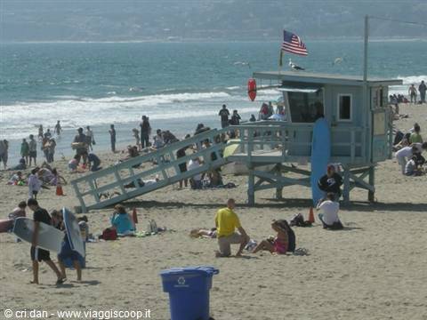 Lifeguard wooden tower with American flag, crowded Santa Monica beach