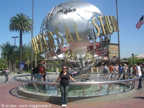 Woman beside the Universal Studios metal globe among palm trees and visitors