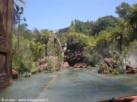 Boats on artificial river among palms and rocky cliffs, water ride in theme park