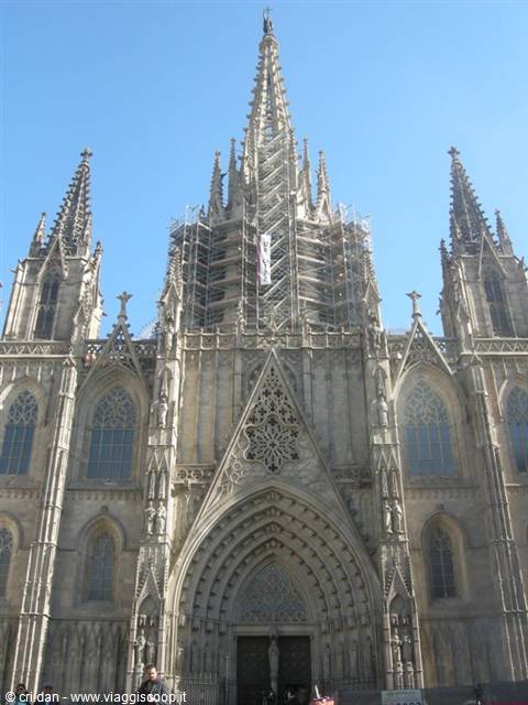 Gothic facade of Barcelona Cathedral with spires and scaffolding under blue sky