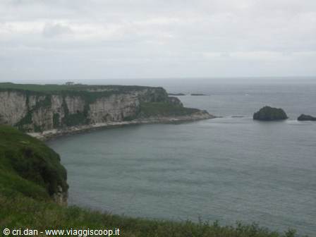 White limestone cliffs plunging into the sea with sea stacks under grey sky