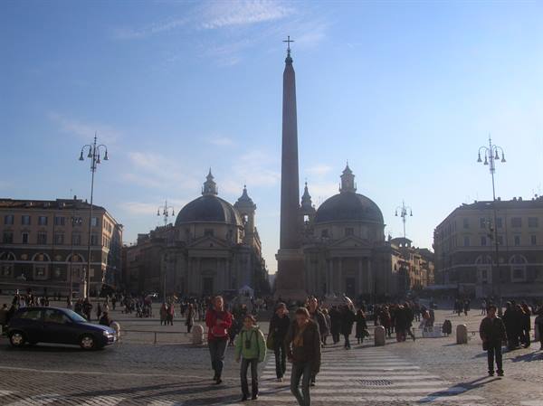 Tourists cross Piazza del Popolo between the Egyptian obelisk and the twin churches