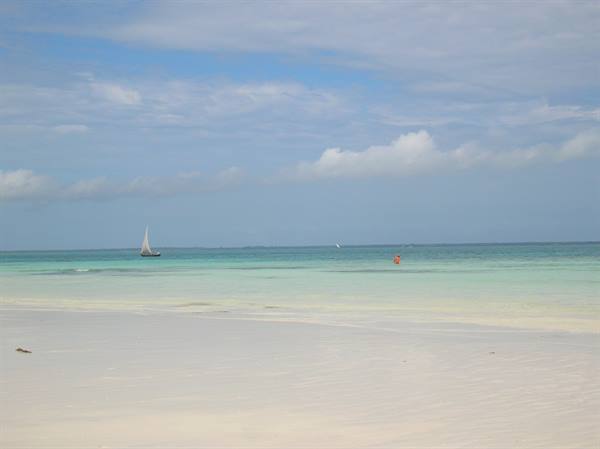 Sailboat on turquoise water off white sand beach, Zanzibar