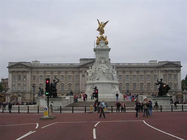 Tourists by the Queen Victoria Memorial in front of Buckingham Palace, grey sky