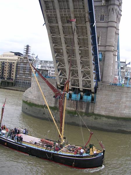 Sailing barge passes under open Tower Bridge on the Thames