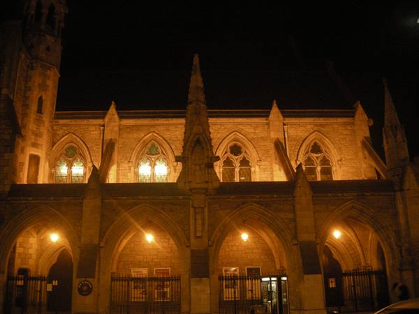 Gothic stone church lit at night, arches and stained glass windows