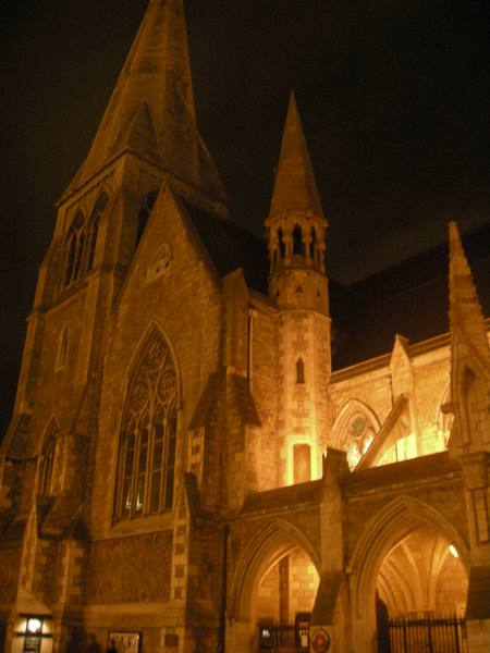 Gothic stone church lit at night, spires and arches glowing amber