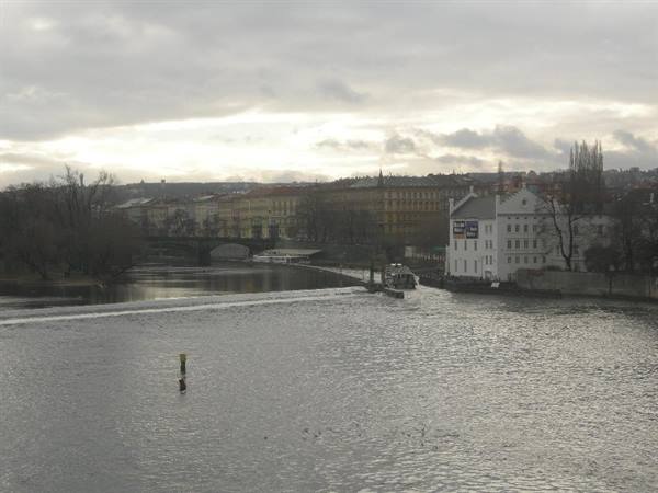 The Vltava river in Prague with a boat moored near a weir