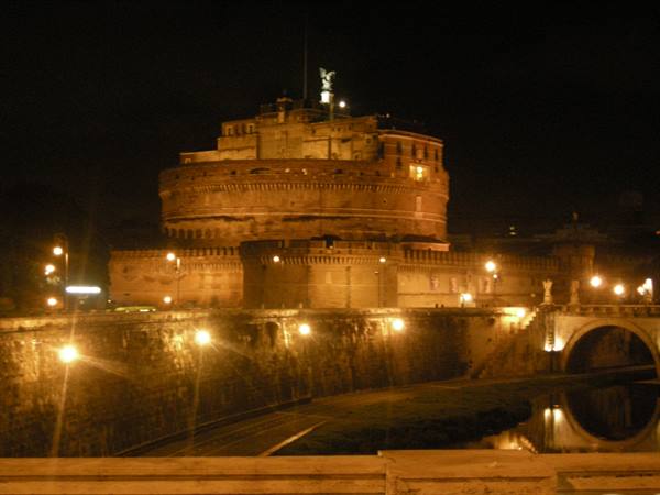 Castel Sant'Angelo lit at night, travertine walls, golden lights reflecting on the Tiber