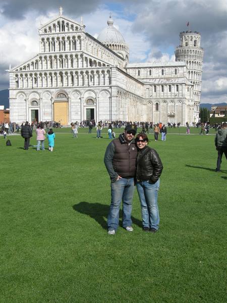 Couple posing on Piazza dei Miracoli lawn, Pisa Cathedral and Leaning Tower behind