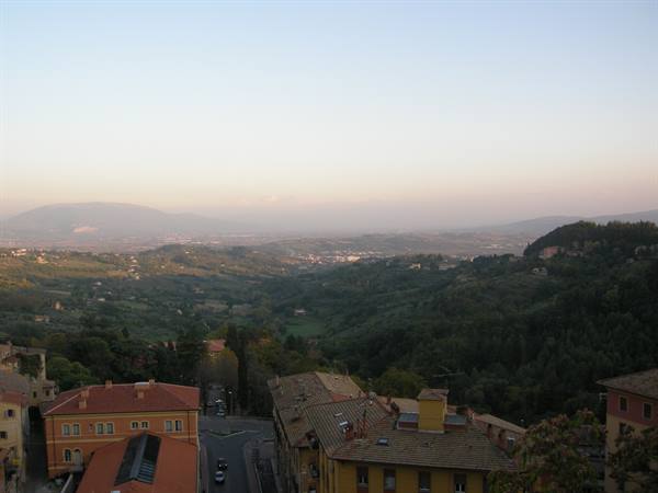 Perugia rooftops above green hills and hazy distant mountains