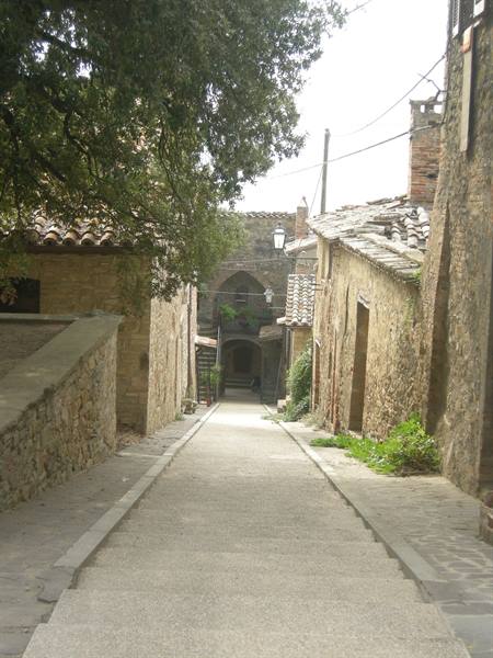 Stepped alley between stone houses with terracotta roofs, soft daylight