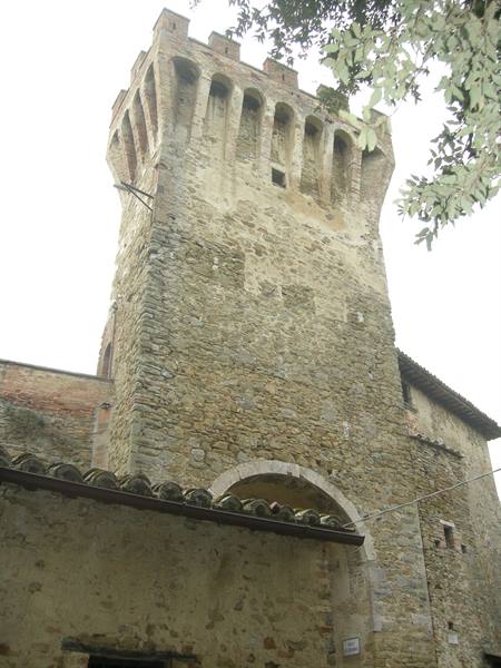 Medieval stone tower with battlements and hanging arches above an archway