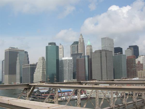 Manhattan skyscrapers behind the steel beams of Brooklyn Bridge