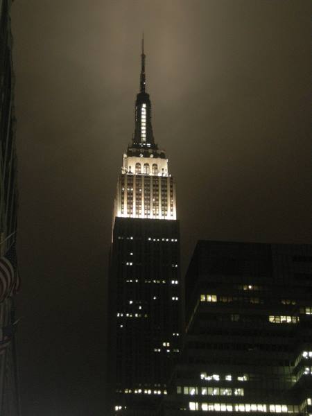 The Empire State Building lit up at night among New York skyscrapers