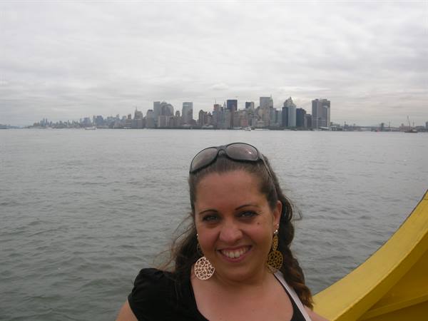 Smiling woman on the ferry with the Manhattan skyline under cloudy skies