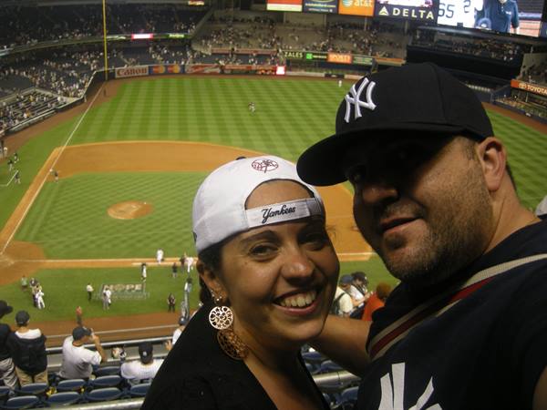 Two Yankees fans wearing caps at Yankee Stadium during an evening game