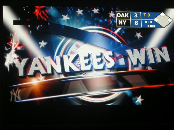 TV screen showing Yankees Win graphic, 8-3 win over Oakland, red and blue sparkles