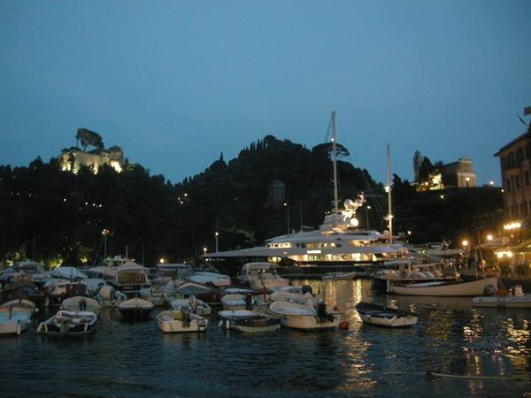 Portofino at dusk: lit yacht and small boats in the harbor, hillside lights