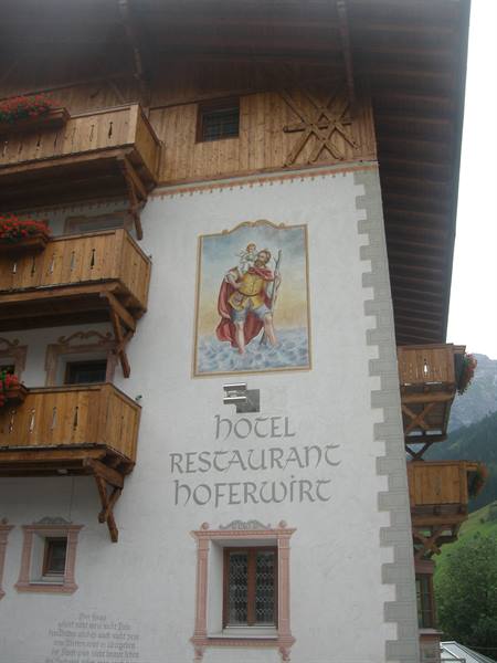 Painted facade of Hotel Restaurant Hoferwirt with wooden balconies and flowers