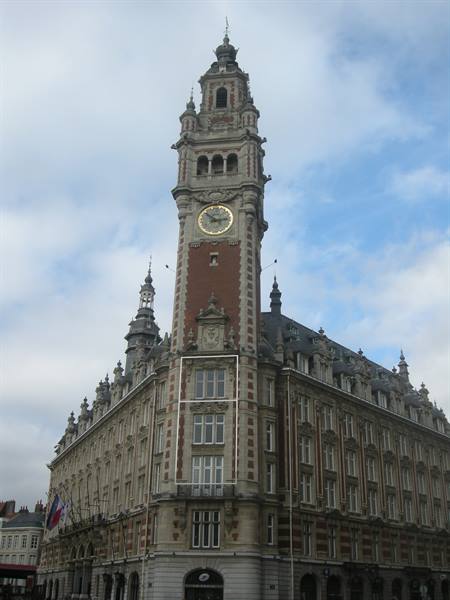 The Chamber of Commerce belfry in Lille with its golden clock beneath a cloudy sky