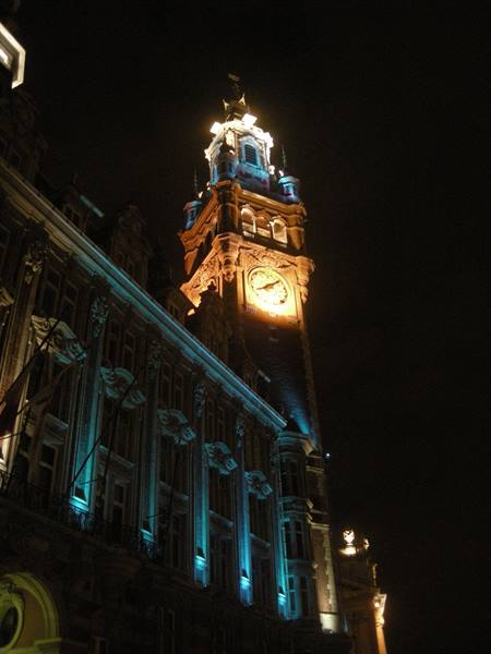 Clock tower lit at night, stone facade with blue lights