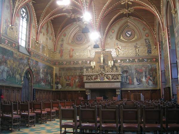 Gothic Hall of Bruges Town Hall: wooden chairs, murals and gilded vault