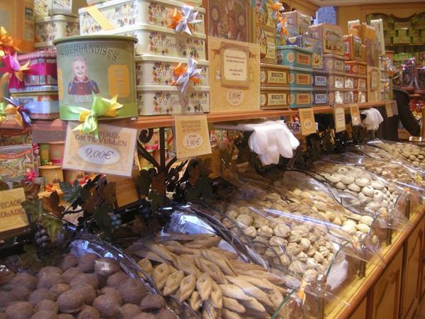 Candy shop counter with decorated tins, wrapped biscuits in clear bags, handwritten price signs