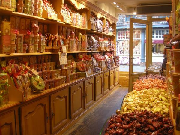 Candy shop with wooden shelves full of tins and sweets