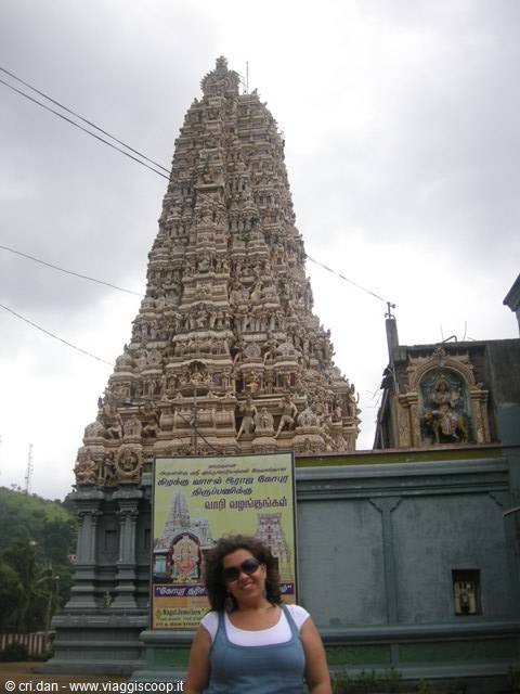 Woman in front of a carved Tamil Hindu temple gopuram, grey sky