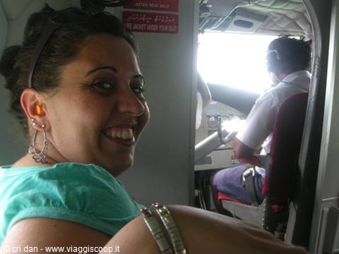 Smiling woman wearing earplugs next to pilot inside small aircraft