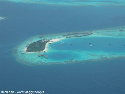 Tropical island with overwater bungalows seen from the plane, turquoise lagoon and coral reef