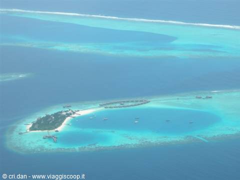 Coral island with overwater bungalows and turquoise lagoon from the air