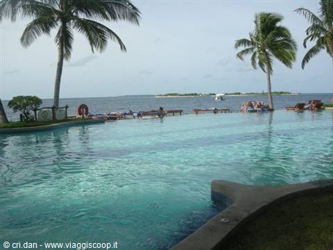 Turquoise pool with palm trees, ocean and islets on the horizon