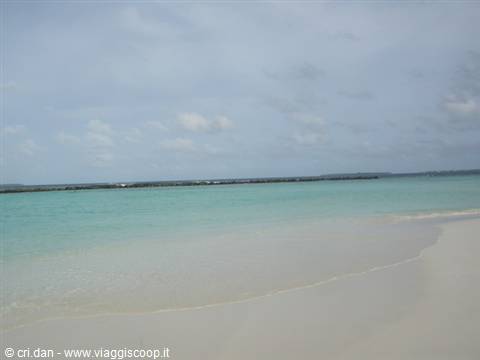 White sand and turquoise water on the beach under a cloudy sky
