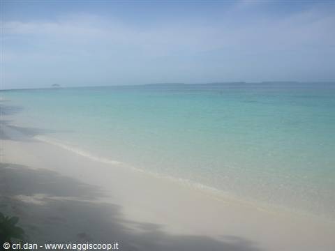 White sand beach, clear turquoise sea and cloudy sky