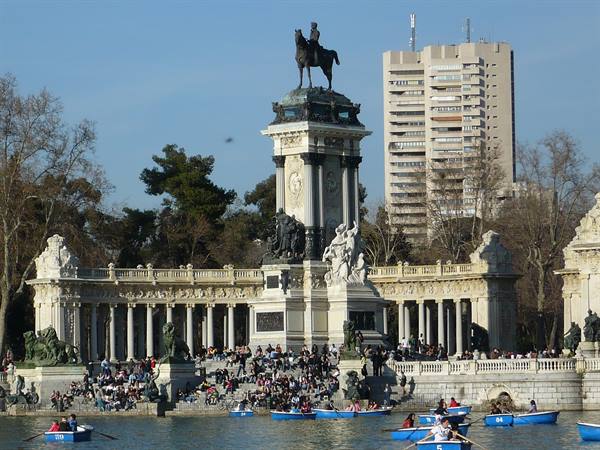 Alfonso XII monument by the Retiro lake in Madrid, rowboats among crowds