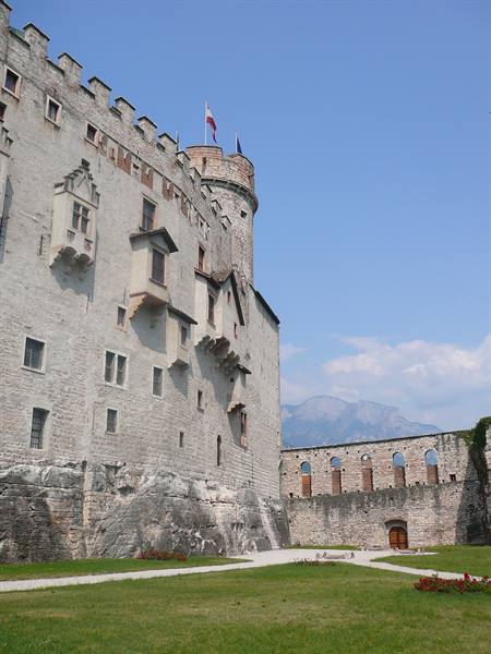 Stone keep with battlements, waving flag and mountains in the background