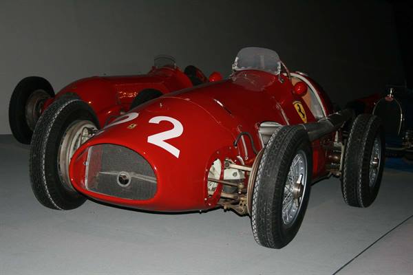 Red vintage Ferrari race car with number 2 displayed indoors