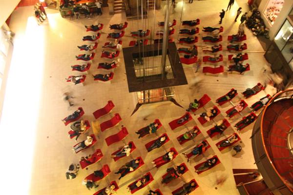 Seen from above, people lying on red loungers inside a museum atrium