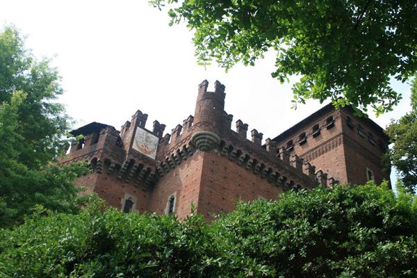 Brick castle with battlements and crest, surrounded by greenery in Borgo Medievale