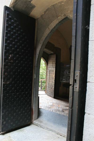 Studded wooden door opening through a stone archway onto a brick floor