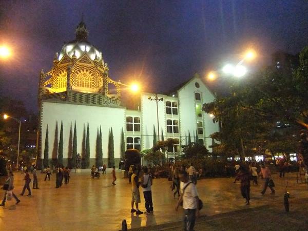 Tourists stroll at night in front of Medellín's Palacio de la Cultura