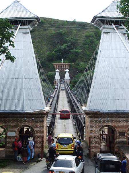Cars queuing on the Puente de Occidente suspension bridge, brick and metal towers