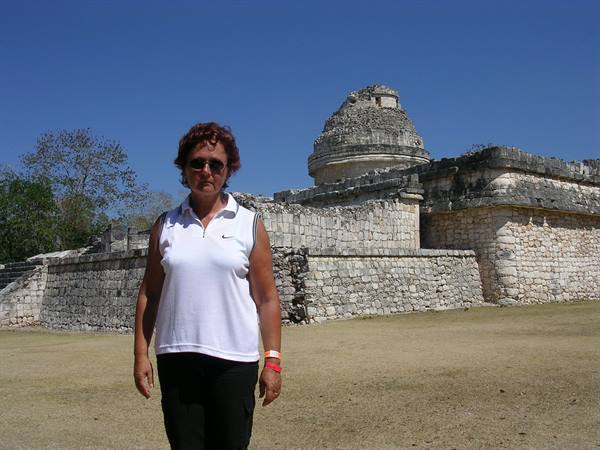 Woman in front of the Maya observatory at Chichén Itzá, limestone under blue sky